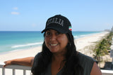Woman wearing a 'ITALIA' cap with a beach and ocean in the background