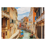 A colorful linen placemat featuring a vibrant print of a canal in Venice with boats and buildings on either side.